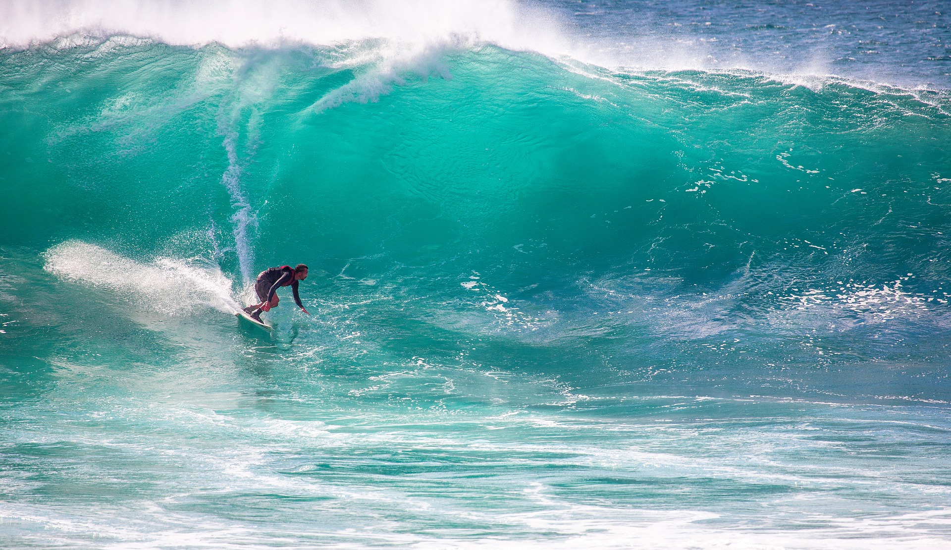 Big wave surfer in light-blue, turquoise water, ocean