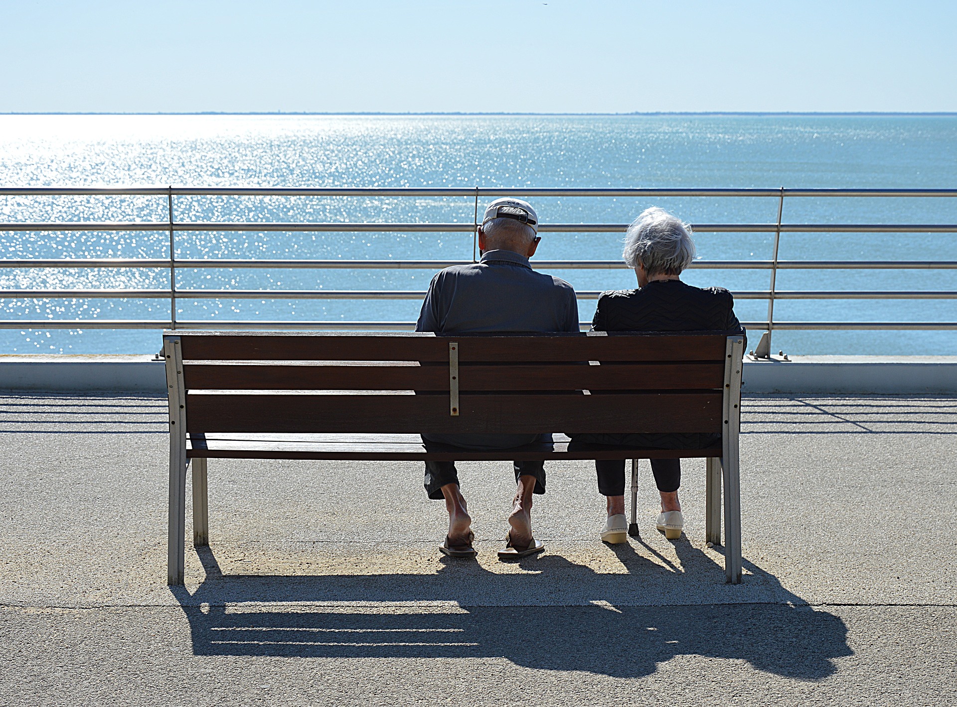 Old couple sitting on a bench next to a lake