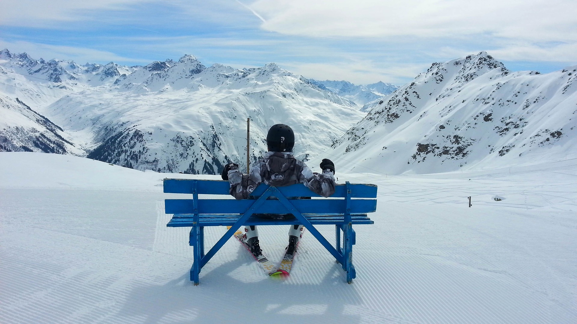 Mountains in Switzerland, Davos. Man with ski sitting on bench.