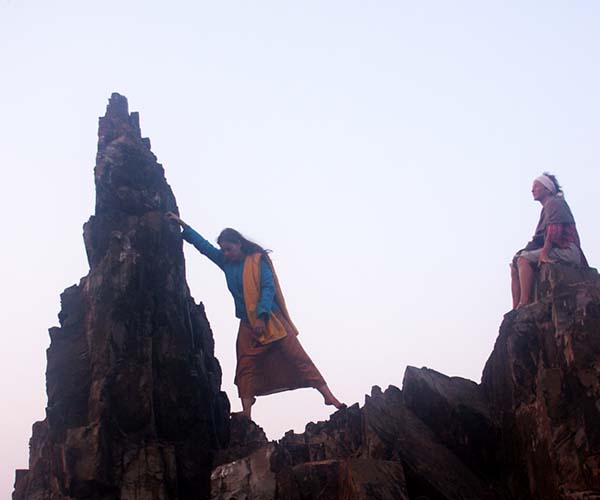 Woman climbing rock in Arambol beach, Goa
