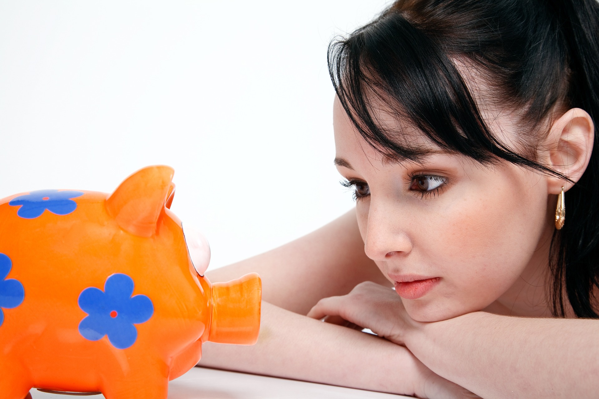 Woman stares at piggy bank: Does she want to save money?