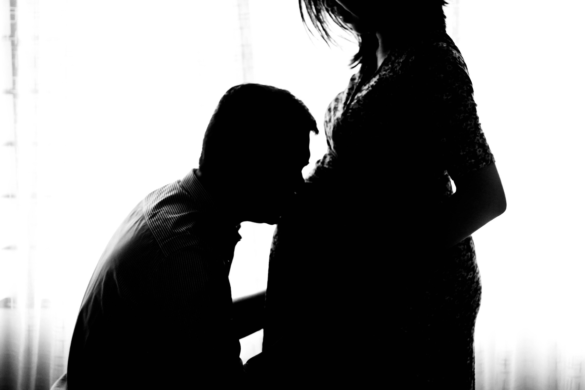 Schwangere Frau: Mann küsst sie auf Bauch