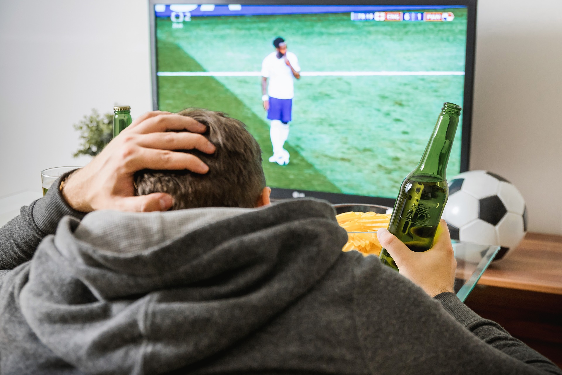 Man drinking in beer in front of TV watching soccer