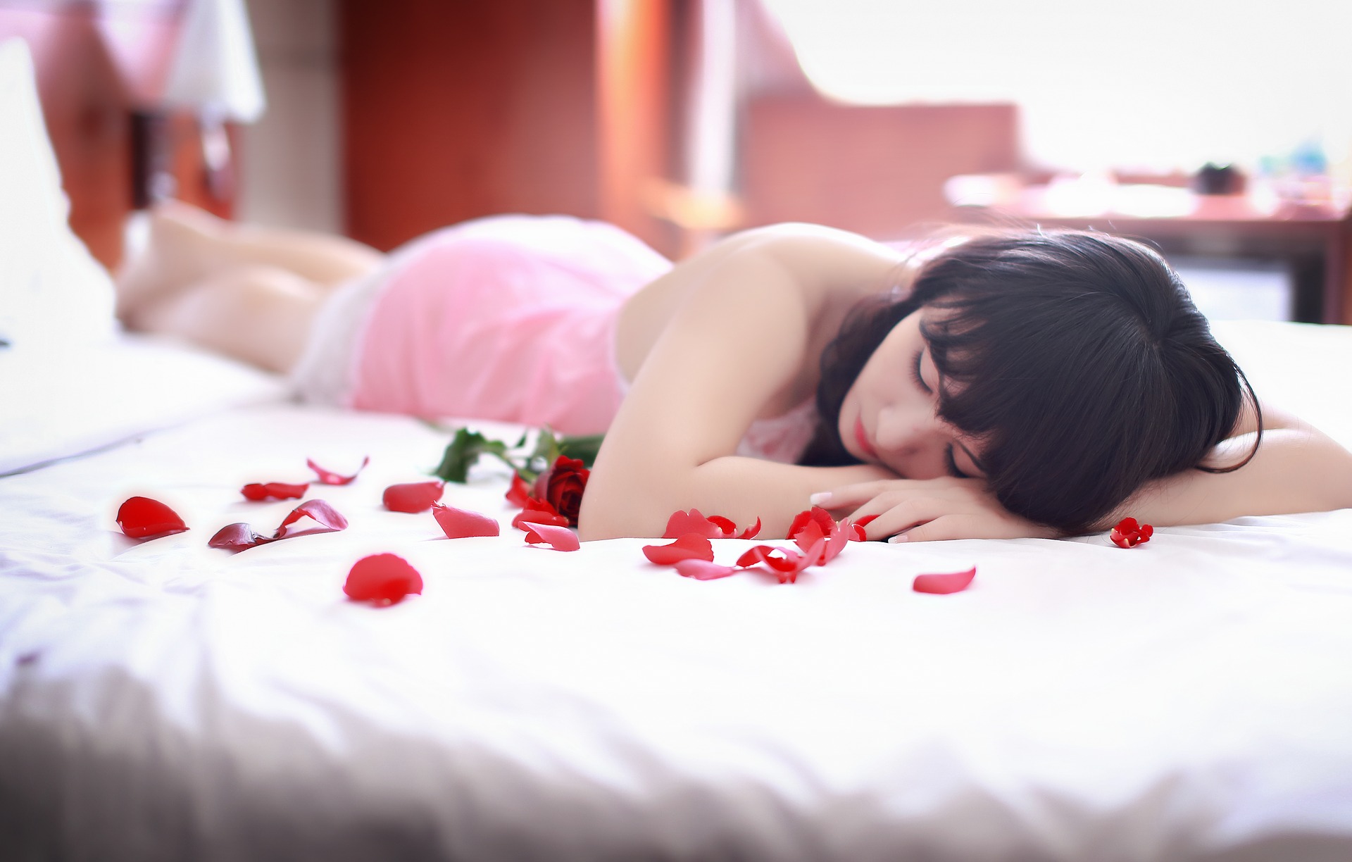 Sad woman in bed with rose petals sleeping